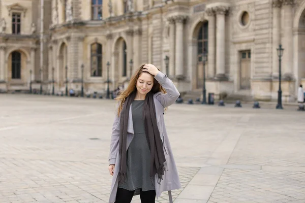 Hübsche Frau im grauen Mantel, die in der Nähe von Raster mit weichem Fokushintergrund steht, Paris. — Stockfoto