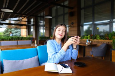 Kadın Café smartphone, defter ve kahve molası.