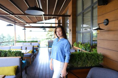 Kadın kişi ile smartpone, sokak kafede ayakta kot gömlek giymiş.