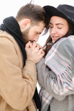Genç portresi sevindirmek eşarp ile ceket giyen adam kadın el beyaz arka planda öpüşme.