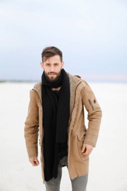 Paltonu ve kaşkolünü beyaz kar arka planda duran giyen sakallı Avrupa genç adam.