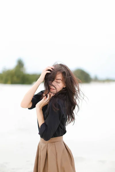 Woman wearing black shirt and skirt standing in white snow monophonic background.