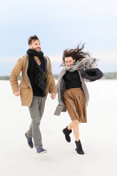 美国男孩和女孩在白色冬天的背景下散步和牵手, 穿着大衣和围巾. — 图库照片