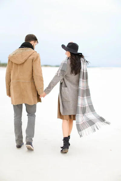 Kadın ve karda yürüme ve elele, erkek ceket, gri atkı ve şapka giyiyor. — Stok fotoğraf