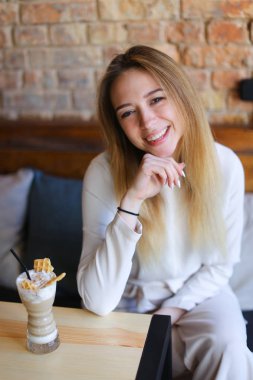 Kadın kahve tabloyla yakınındaki ahşap sandalye üzerinde oturan ve bir fotoğraf için poz.