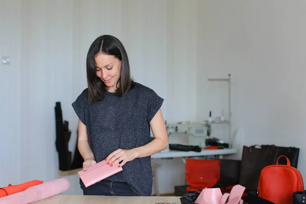 Креативна жінка робить рожевий шкіряний гаманець вдома в ательє . — стокове фото