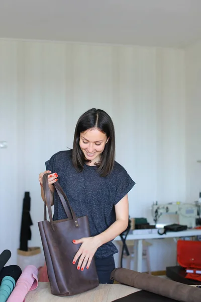 Mulher feliz fazendo saco de couro marrom artesanal no atelier . — Fotografia de Stock