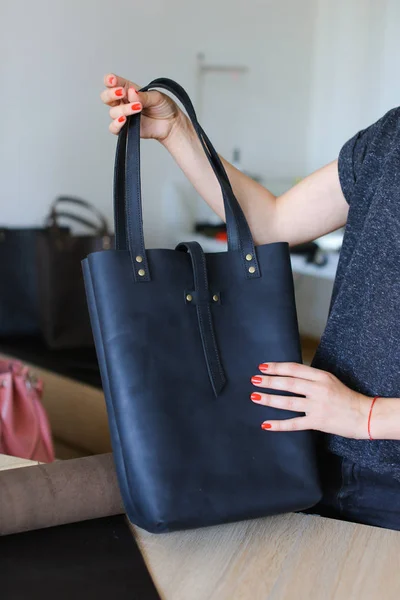 Persona femminile che tiene donna nera borsa in pelle fatta a mano in atelier . — Foto Stock