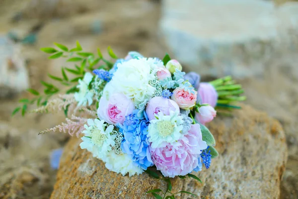 Buquê de flores azuis, rosa e brancas deitadas sobre pedras . — Fotografia de Stock