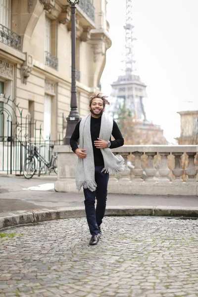 아프리카 미국 남성 사람이 에펠 탑과 백그라운드에서 실행 회색 스카프와 검은 스웨터를 입고. — 스톡 사진