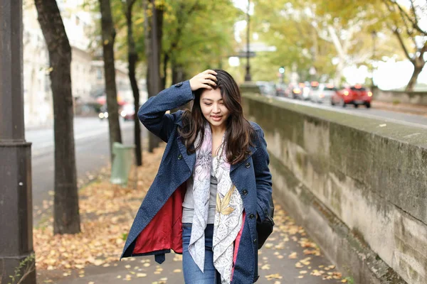 Chinesische hübsche Touristin spaziert auf Herbststraße mit umgefallenen Blättern in Europa. — Stockfoto