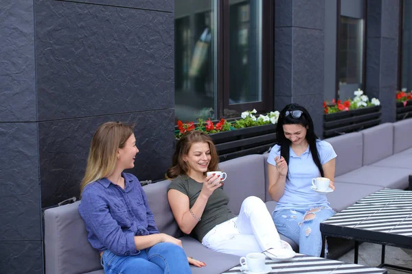 Hermosas amigas riendo en la cafetería y chismorreando, bebiendo café . — Foto de Stock