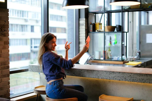 Attraktives Mädchen macht Selfie mit Smartphone in Café-Bar. — Stockfoto