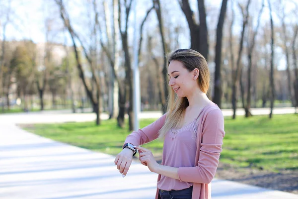 Giovane ragazza a piedi nel parco e utilizzando orologio intelligente . — Foto Stock