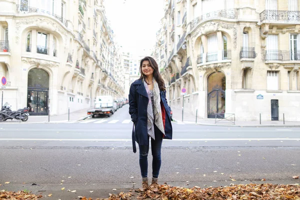 Çinli güzel uluslararası öğrenci düşen yapraklar ile sokakta duran.