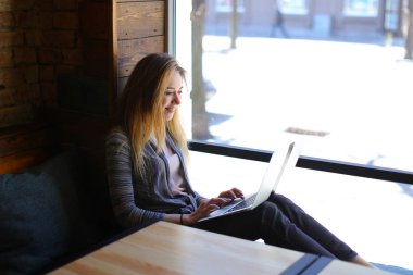 Masanın defter ile ve fincan kapuçino tutan kız gülümseyerek.