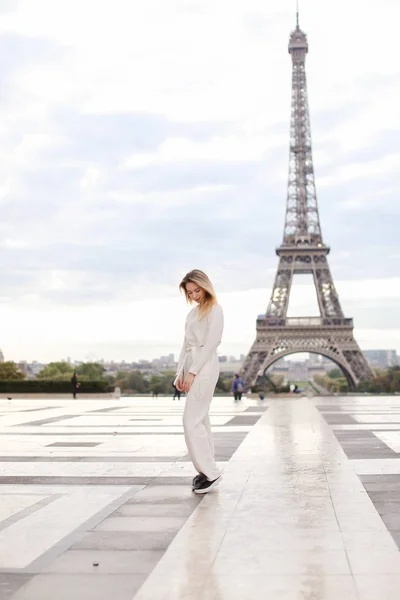 Stijlvolle mooie vrouw in de buurt van Eiffel Tower in witte overalls. — Stockfoto