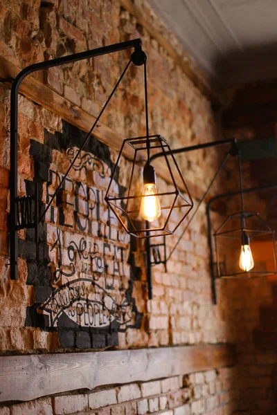 Pared de ladrillo con lámparas en una cafetería extraordinaria . — Foto de Stock