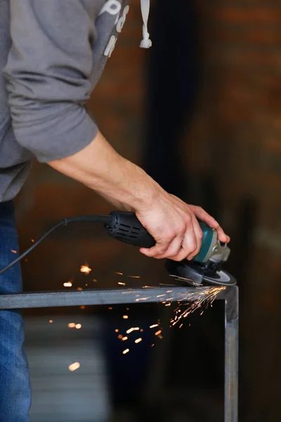 Strong male hands sawing metall construction by electrical tool.