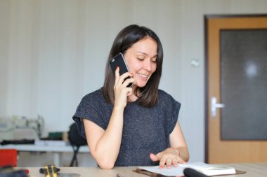 Smartphone ile konuşmak ve el yapımı deri dizüstü evde oluşturma güzel craftswoman.