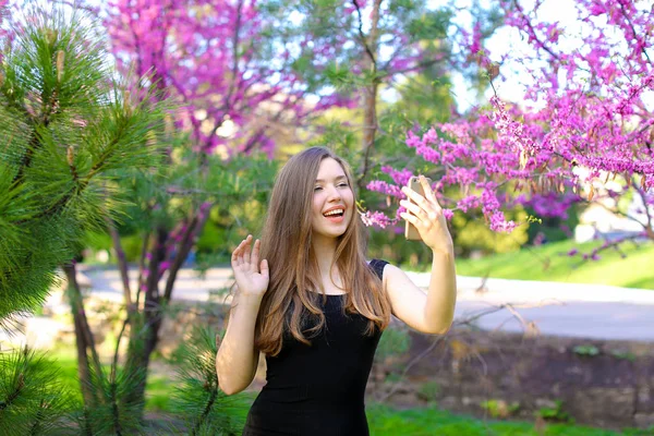 Kvinna att göra selfie av smartphone med spring blossom bakgrund. — Stockfoto