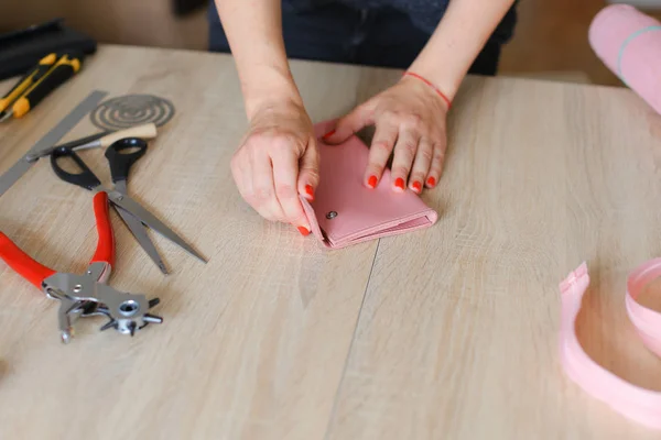 女性手用红色钉子制作粉红色皮革钱包与工具在画室里. — 图库照片