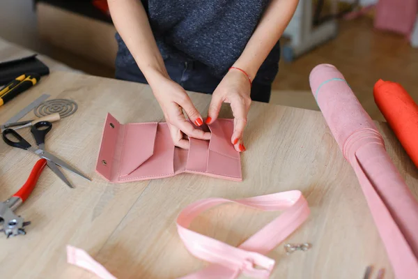 Γυναικείο πρόσωπο δημιουργώντας ροζ Δερμάτινο χειροποίητο πορτοφόλι στο σπίτι. — Φωτογραφία Αρχείου