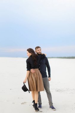 Hugginng etek giyen ve şapka, kış kar arka plan tutmak gülümseyen genç yakışıklı adam.