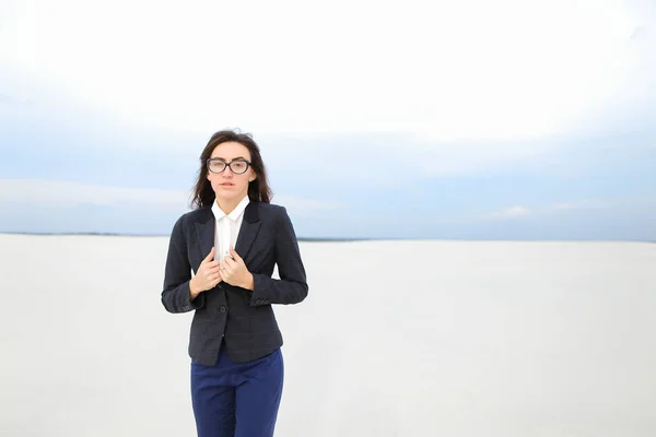 Female beautiful secretary standing on snow and wearing jacket with glasses.