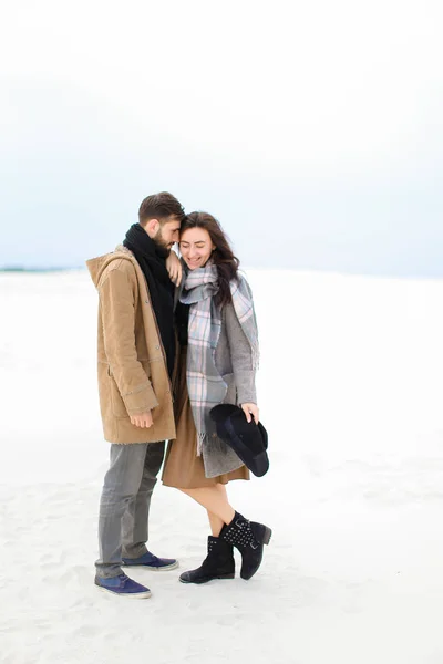 Jonge vrouw grijze sjaal staande met man dragen met vacht, winter witte achtergrond. — Stockfoto