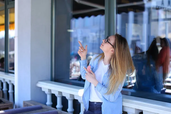 Flickan tittar upp med pekfingret och hålla smartphone. — Stockfoto