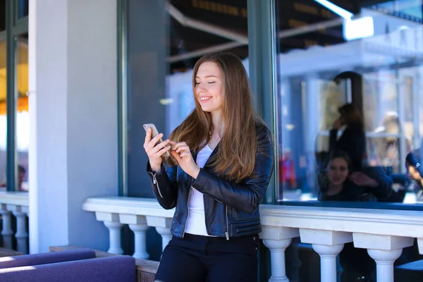 Hübsche Frau plaudert per Smartphone im Straßencafé. — Stockfoto