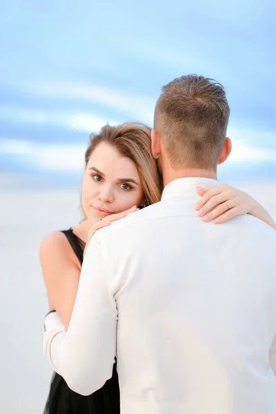 Giovane donna bionda abbracciare l'uomo in sfondo campo bianco . — Foto Stock
