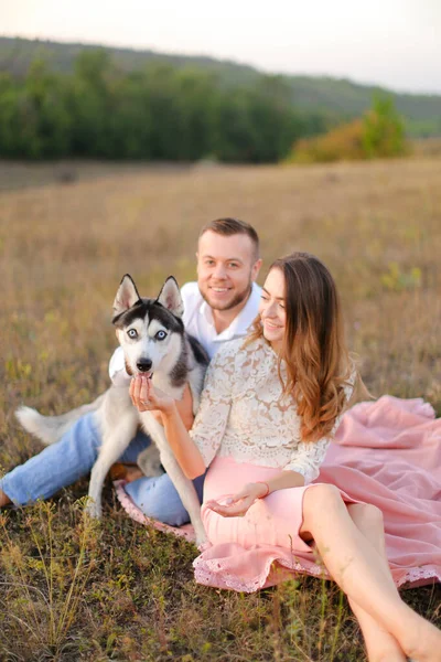 Young girl and man sitting on gras with husky. — Stock Photo, Image