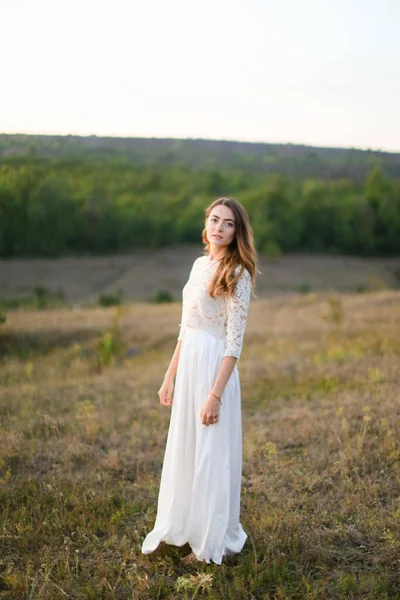 Caucasian bride standing in steppe and wearing white dress. — Stock Photo, Image