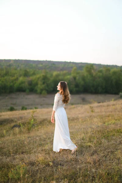 Caucasian young woman walking in steppe and wearing white dress. — Stock Photo, Image
