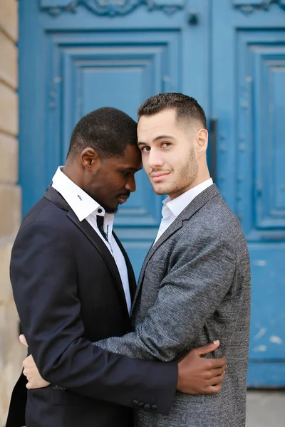 Afro-Amerikaanse knappe man knuffelen Kaukasische jongen in deur achtergrond. — Stockfoto