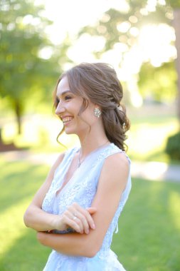 Bahçede yürüyen, gülümseyen bir gelin.