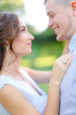 Gelin, yeşil arka planda damadı kucaklıyor..