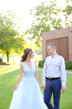 Beyaz tenli güzel gelin damat ile bahçede yürüyor..