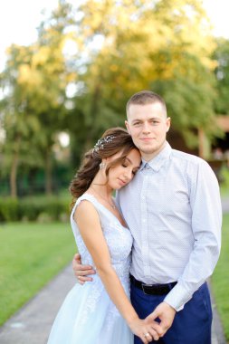 Genç, hoş bir gelin bahçede beyaz damatla sarılıyor..