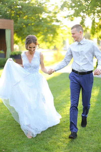 Cacuasian fästmö promenader med brudgum i parken och hålla händer. — Stockfoto