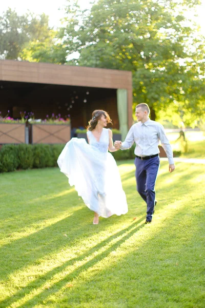 Κακασιάτισσα νύφη περπατώντας με τον γαμπρό στο πάρκο και κρατώντας τα χέρια. — Φωτογραφία Αρχείου