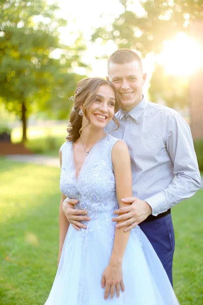 公園で幸せな笑顔新郎抱擁の花嫁、太陽の光. — ストック写真