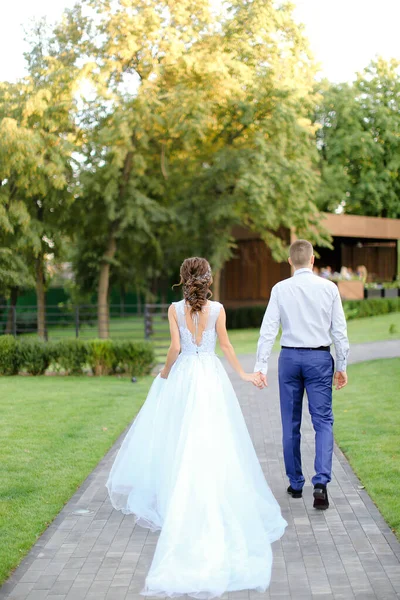 Achteraanzicht van blanke verloofde en bruidegom gaat naar buiten. — Stockfoto