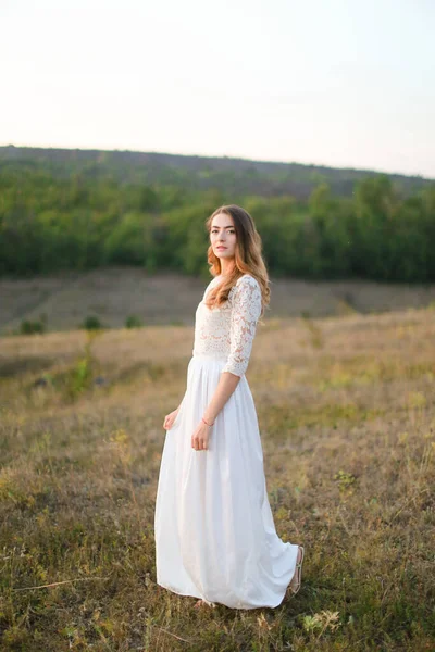 Λευκή όμορφη νύφη στέκεται στη στέπα και φοράει λευκό φόρεμα. — Φωτογραφία Αρχείου