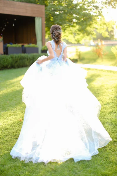 Πίσω όψη της νύφης με τα πόδια στο πάρκο και φορώντας λευκό φόρεμα. — Φωτογραφία Αρχείου