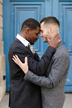 Afro-Amerikan gülümseyen adam, arka planda beyaz çocuğu kucaklıyor..