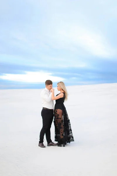 Young boy in white shirt hugging woman wearing black dress in winter steppe. — Stock Photo, Image