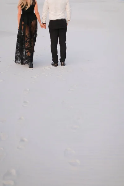 Visão traseira do homem e da menina vestindo vestido preto andando na estepe nevada . — Fotografia de Stock
